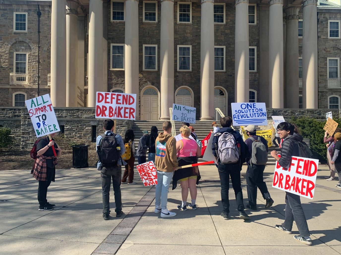 Protesters hold signs in support of Oliver Baker outside of Penn State's Old Main building
